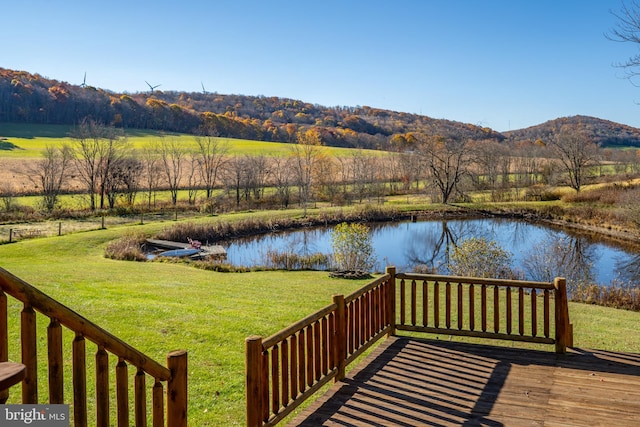 wooden terrace featuring a water and mountain view, a rural view, and a yard