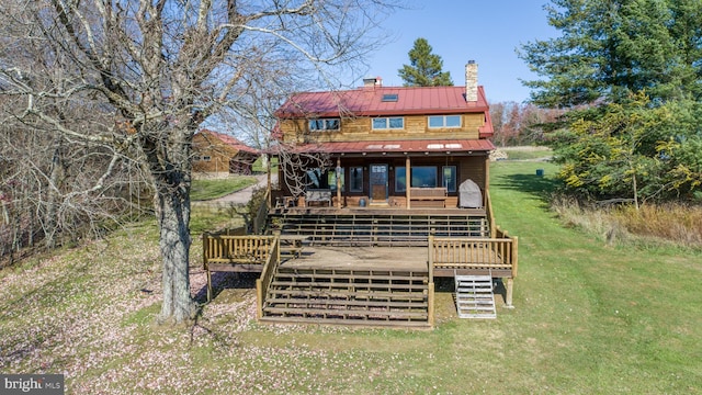 rear view of house featuring a lawn and a deck