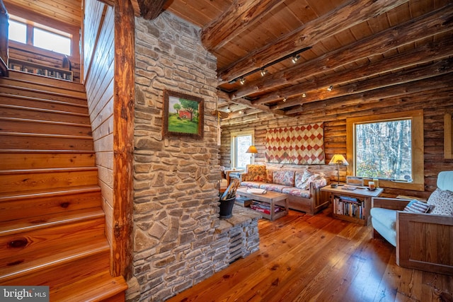 living room featuring a wealth of natural light, wood-type flooring, and beamed ceiling