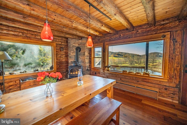 dining space with beamed ceiling, hardwood / wood-style floors, wooden ceiling, and a wood stove