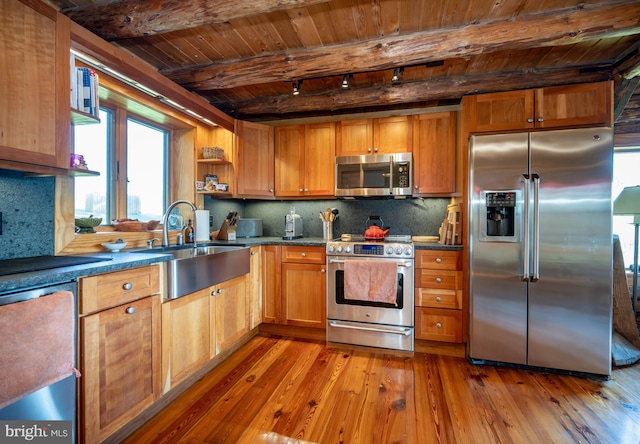 kitchen featuring sink, appliances with stainless steel finishes, tasteful backsplash, beam ceiling, and light wood-type flooring