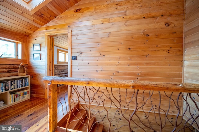 interior space with vaulted ceiling with skylight, wood-type flooring, wood ceiling, and wooden walls