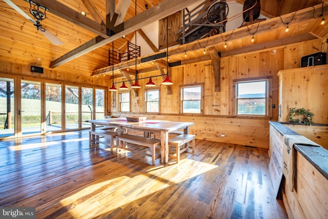 dining room featuring high vaulted ceiling, light hardwood / wood-style flooring, wood walls, and beam ceiling