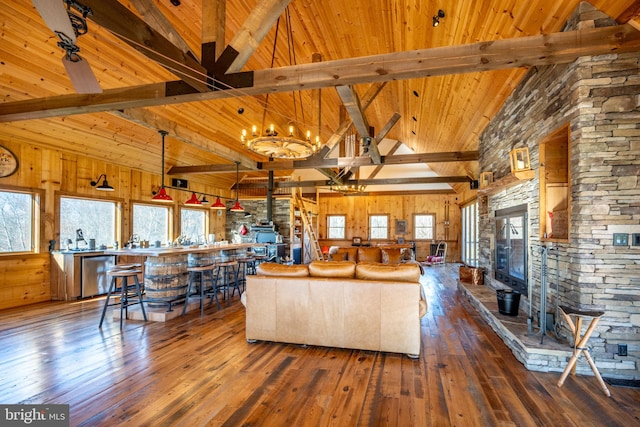 unfurnished living room featuring dark wood-type flooring, a wealth of natural light, wooden walls, and a notable chandelier