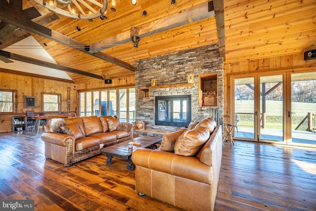 living room with a stone fireplace, beamed ceiling, a wealth of natural light, and hardwood / wood-style flooring