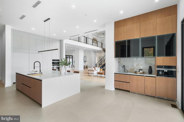 kitchen featuring a spacious island, sink, pendant lighting, and tasteful backsplash