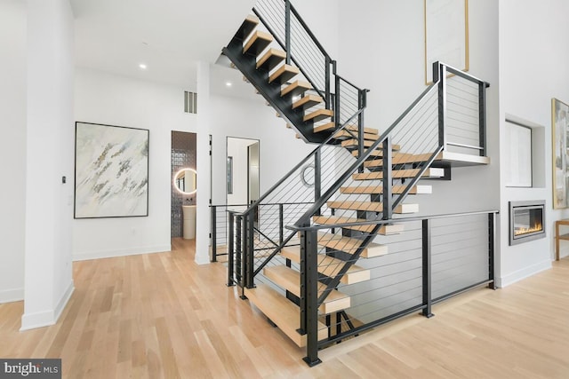 stairs featuring a towering ceiling and hardwood / wood-style floors