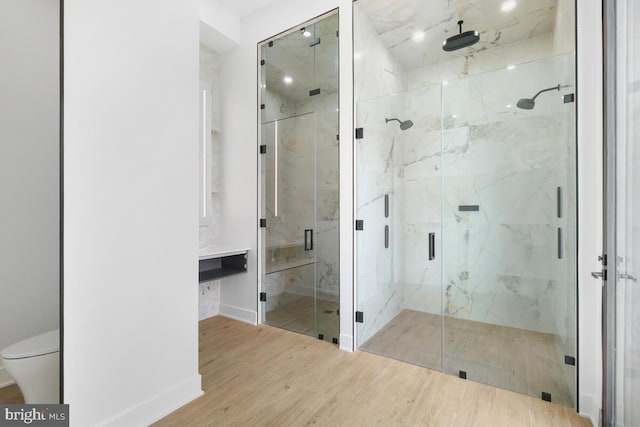 bathroom with hardwood / wood-style floors, a shower with shower door, and toilet