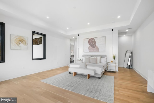 bedroom featuring light hardwood / wood-style floors and a tray ceiling