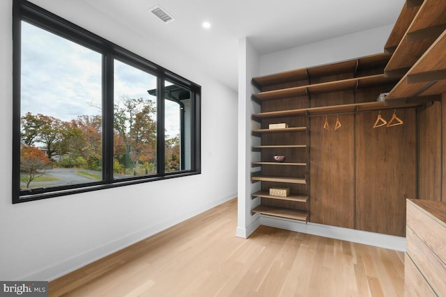 walk in closet with light hardwood / wood-style floors