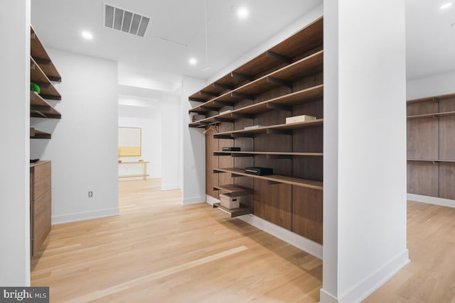 walk in closet with light hardwood / wood-style flooring