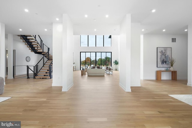 interior space featuring a towering ceiling and light hardwood / wood-style flooring