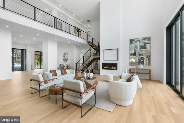 living room featuring a towering ceiling and light wood-type flooring