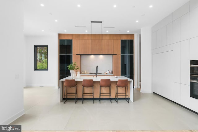 kitchen featuring hanging light fixtures, a breakfast bar area, sink, and a large island