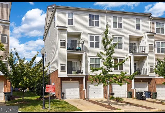 townhome / multi-family property with a garage, a front yard, and a balcony