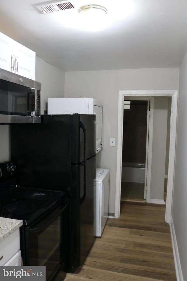 kitchen featuring white cabinetry, stacked washing maching and dryer, electric range, and dark hardwood / wood-style floors