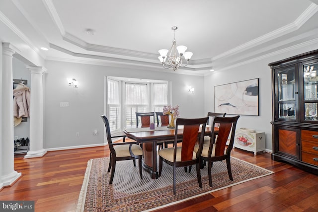 dining room with dark wood-type flooring, a tray ceiling, and ornate columns