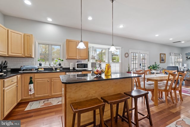 kitchen with plenty of natural light, hanging light fixtures, dark hardwood / wood-style floors, and a kitchen island