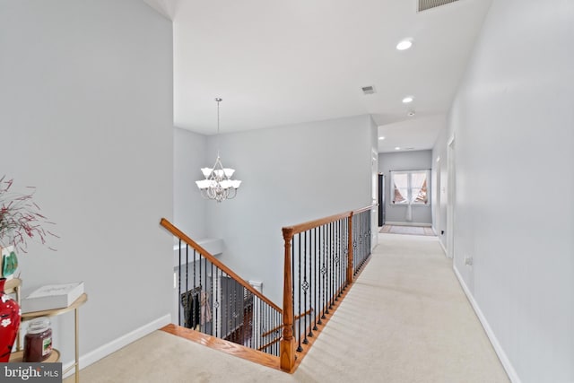 hall with light carpet and a chandelier