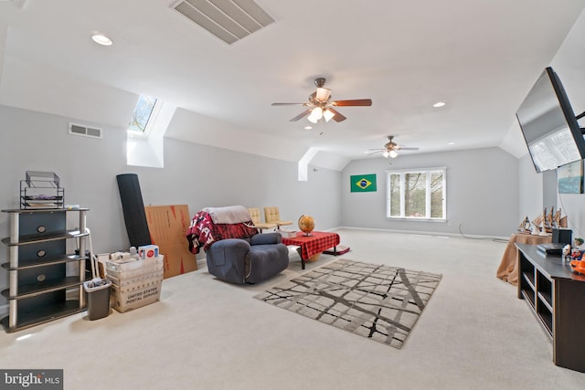 interior space with vaulted ceiling with skylight, ceiling fan, and light carpet