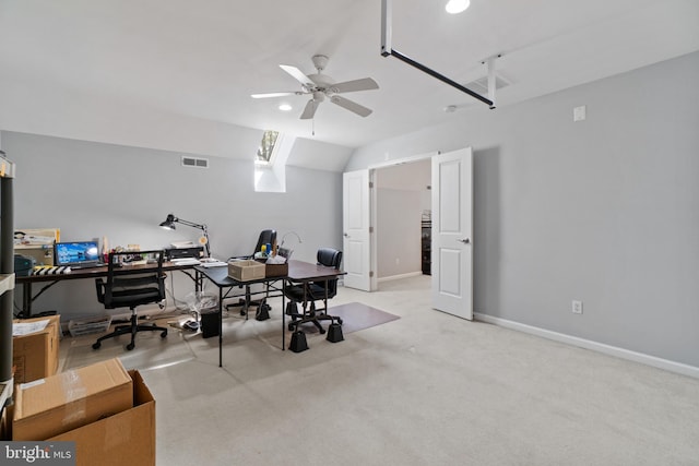 carpeted home office featuring vaulted ceiling with skylight and ceiling fan