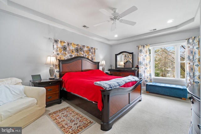 bedroom with ceiling fan, light carpet, and a raised ceiling