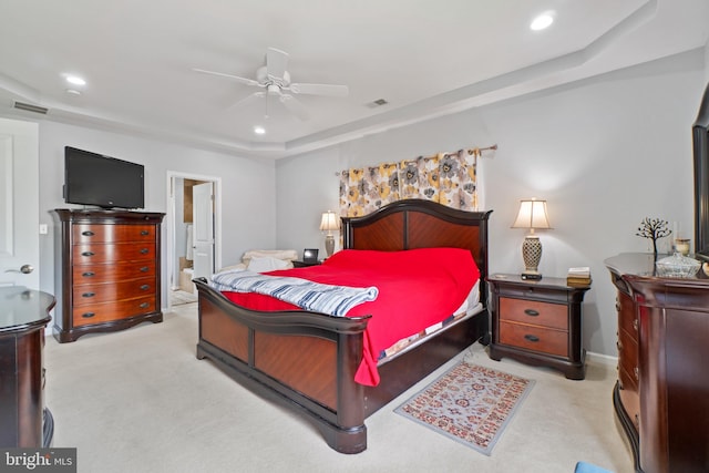 carpeted bedroom with ensuite bath, ceiling fan, and a raised ceiling