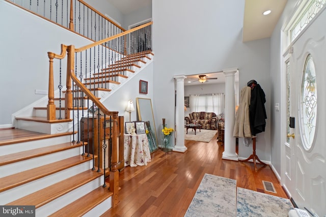 foyer featuring hardwood / wood-style flooring, a high ceiling, and decorative columns