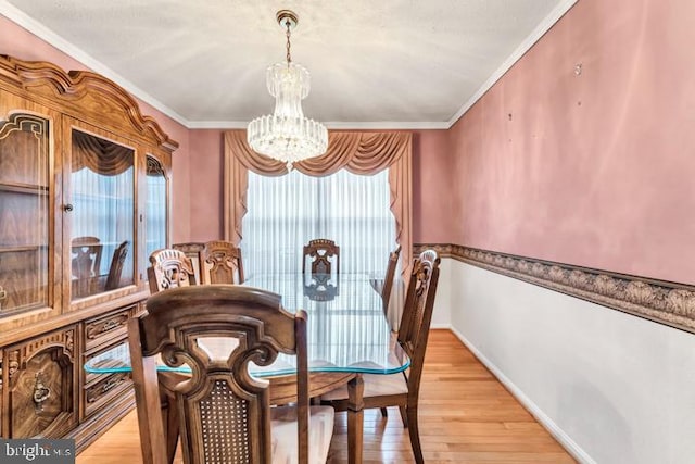 dining area with ornamental molding, light wood-type flooring, plenty of natural light, and a notable chandelier