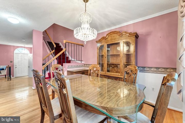 dining room featuring light hardwood / wood-style floors, crown molding, and an inviting chandelier