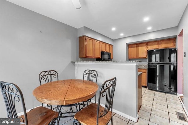 kitchen featuring kitchen peninsula, black appliances, light tile patterned floors, and light stone countertops