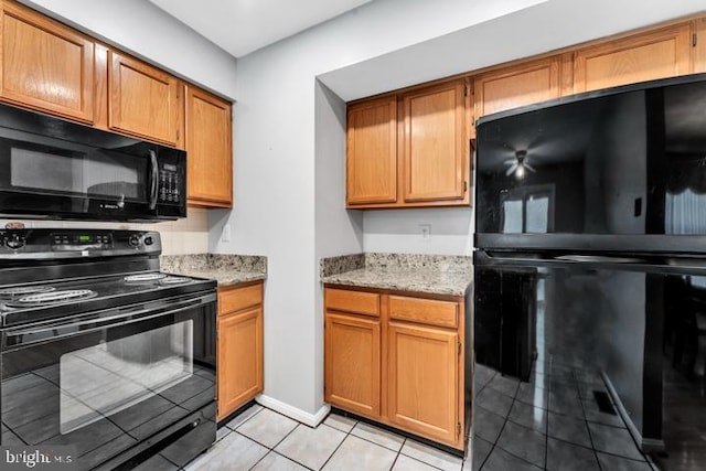 kitchen with black appliances, light stone counters, and light tile patterned floors