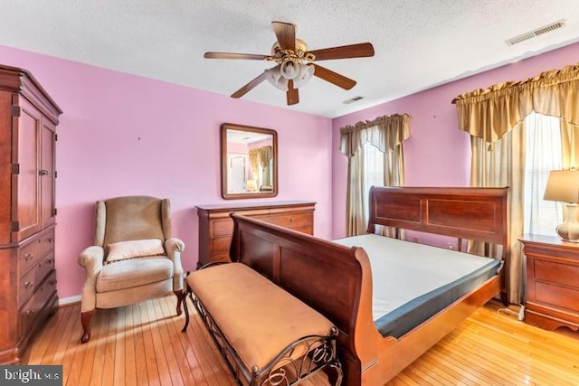 bedroom featuring light wood-type flooring, a textured ceiling, and ceiling fan