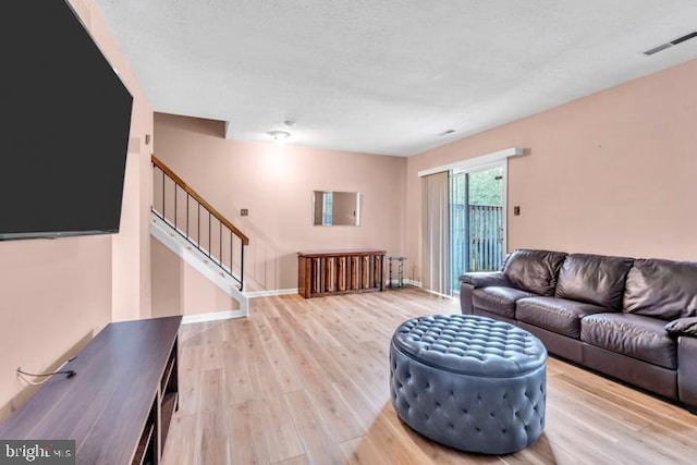 living room featuring light wood-type flooring and a textured ceiling