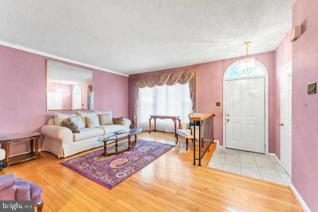 foyer with a textured ceiling, light hardwood / wood-style flooring, and crown molding