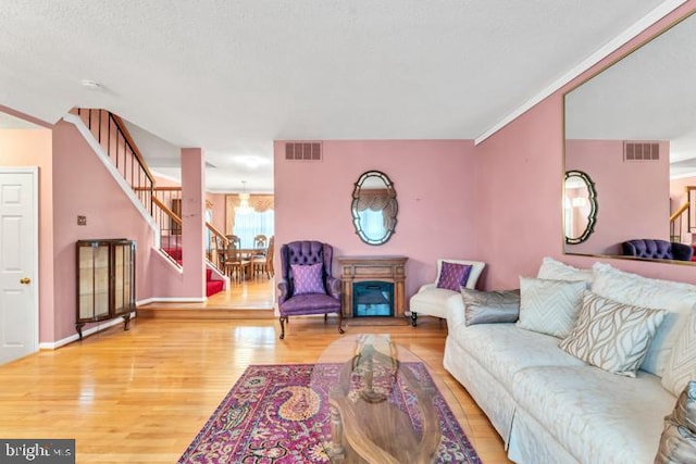 living room featuring hardwood / wood-style flooring, a textured ceiling, and crown molding