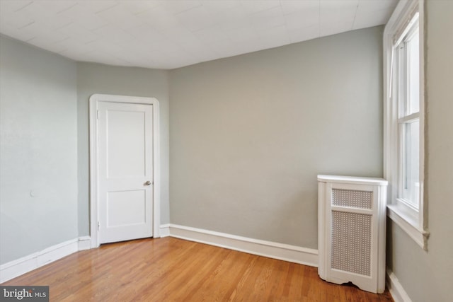 spare room with light hardwood / wood-style floors and radiator heating unit