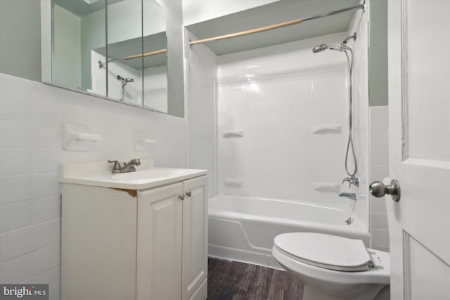 full bathroom with shower / washtub combination, hardwood / wood-style flooring, tile walls, toilet, and vanity