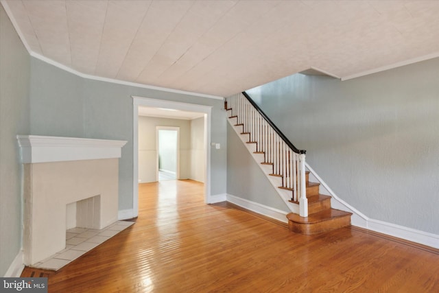 unfurnished living room with light hardwood / wood-style floors, ornamental molding, and a fireplace