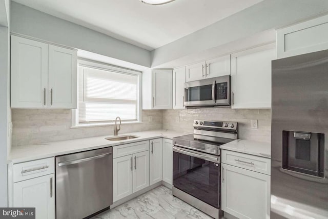 kitchen with decorative backsplash, light stone counters, white cabinetry, sink, and stainless steel appliances