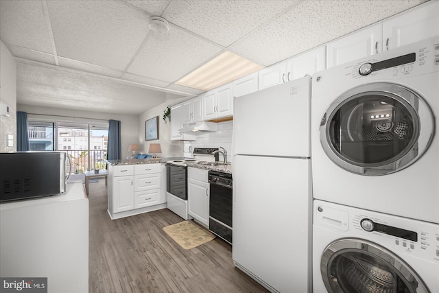 kitchen with dark wood-type flooring, white appliances, stacked washer and dryer, and white cabinets