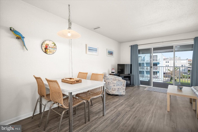 dining area with dark wood-type flooring and a textured ceiling