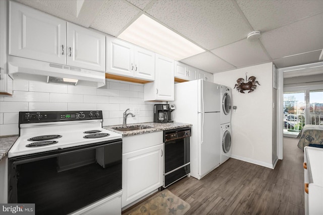 kitchen featuring white cabinetry, stacked washer and clothes dryer, white appliances, and sink