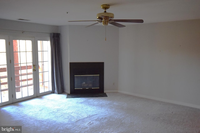 unfurnished living room featuring carpet, plenty of natural light, visible vents, and a ceiling fan