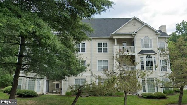 rear view of house with a yard and a balcony