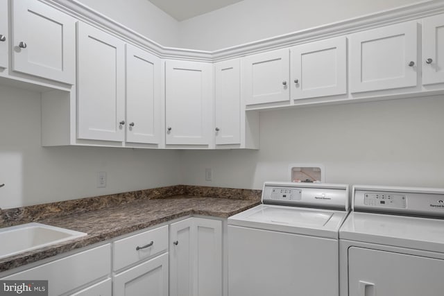 clothes washing area featuring cabinets, sink, and separate washer and dryer