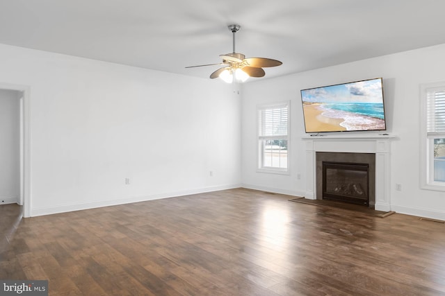 unfurnished living room with dark hardwood / wood-style floors, a healthy amount of sunlight, and ceiling fan