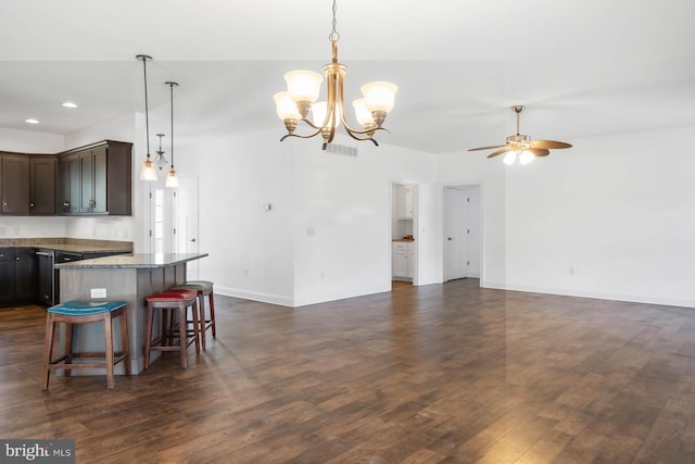 kitchen featuring dark brown cabinets, dark hardwood / wood-style flooring, a kitchen bar, ceiling fan with notable chandelier, and light stone counters