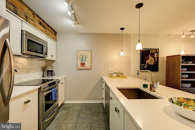 kitchen with stainless steel appliances, dark tile patterned floors, hanging light fixtures, sink, and white cabinets