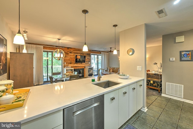 kitchen featuring decorative light fixtures, wood walls, a wealth of natural light, sink, and stainless steel dishwasher